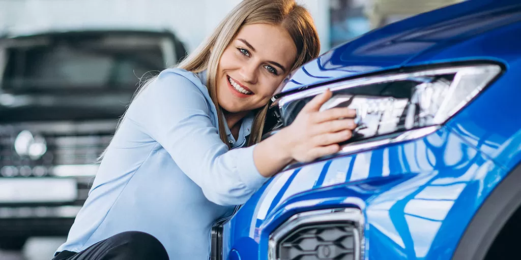 Woman hugging her blue car.