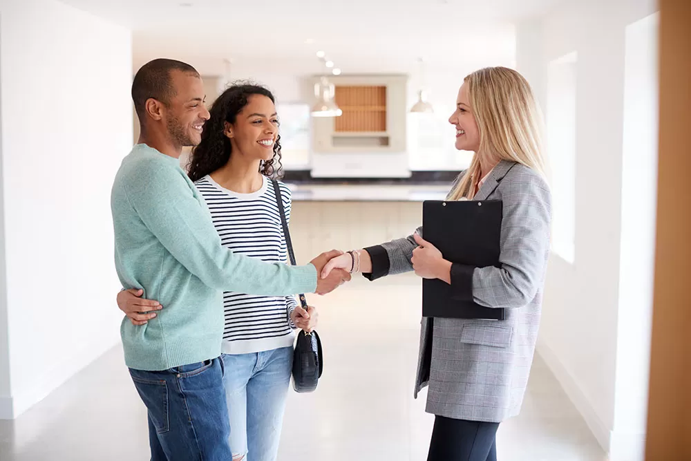 realtor shaking couples hands in home